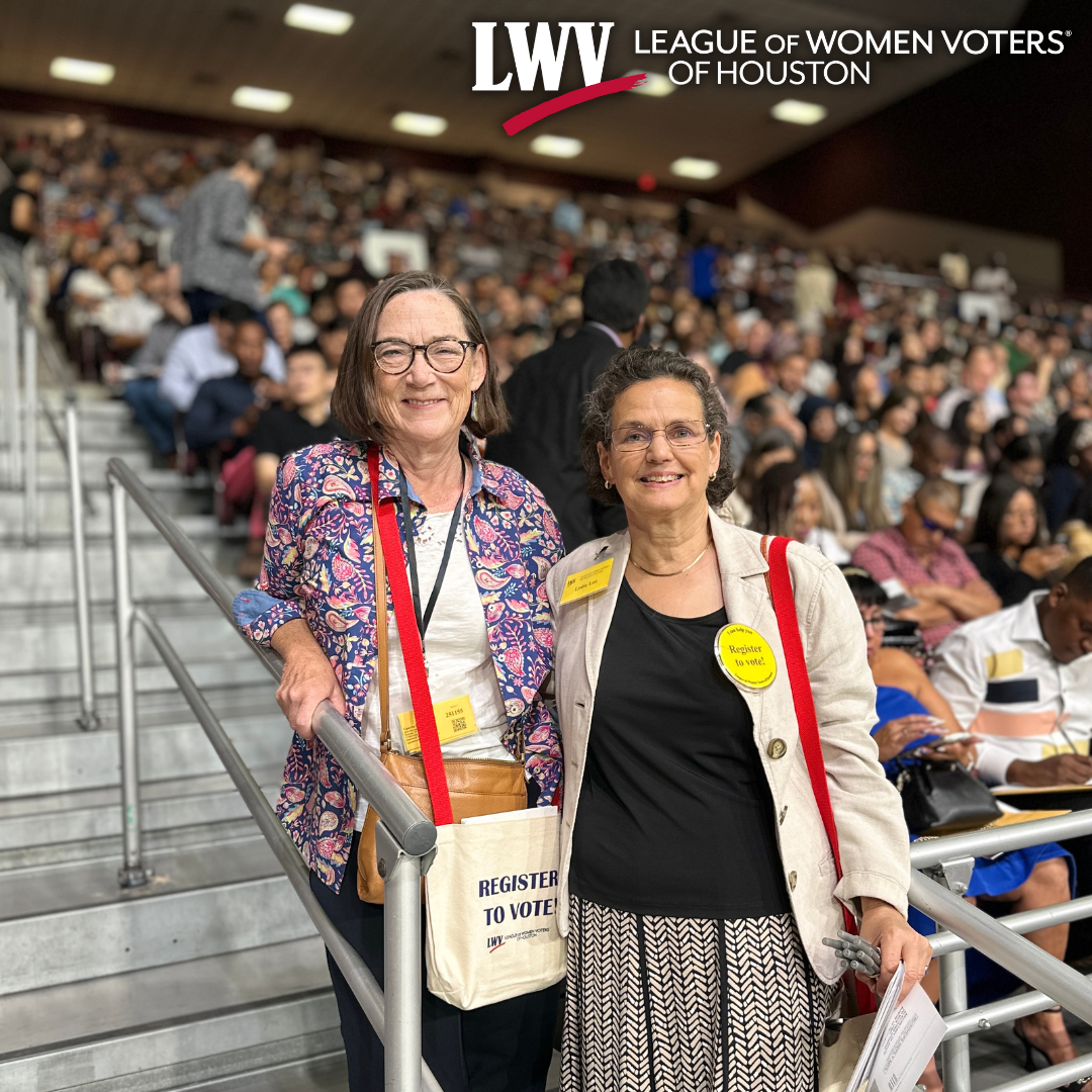 Two women are standing next to each other in a crowded stadium.