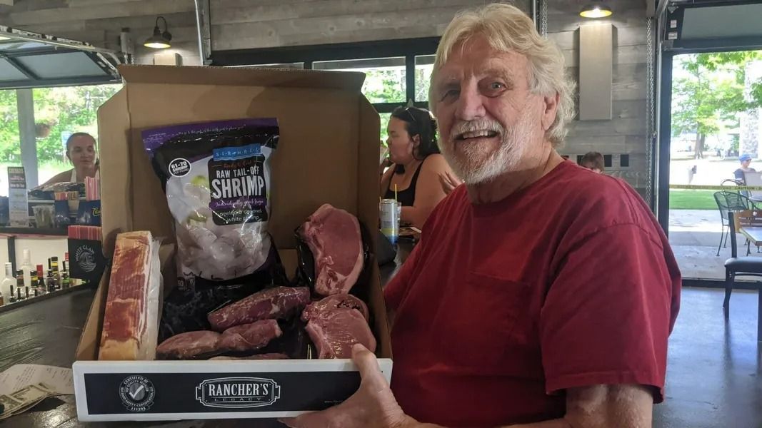 Man holding a large display tray of smoked meat at an indoor market or food stall