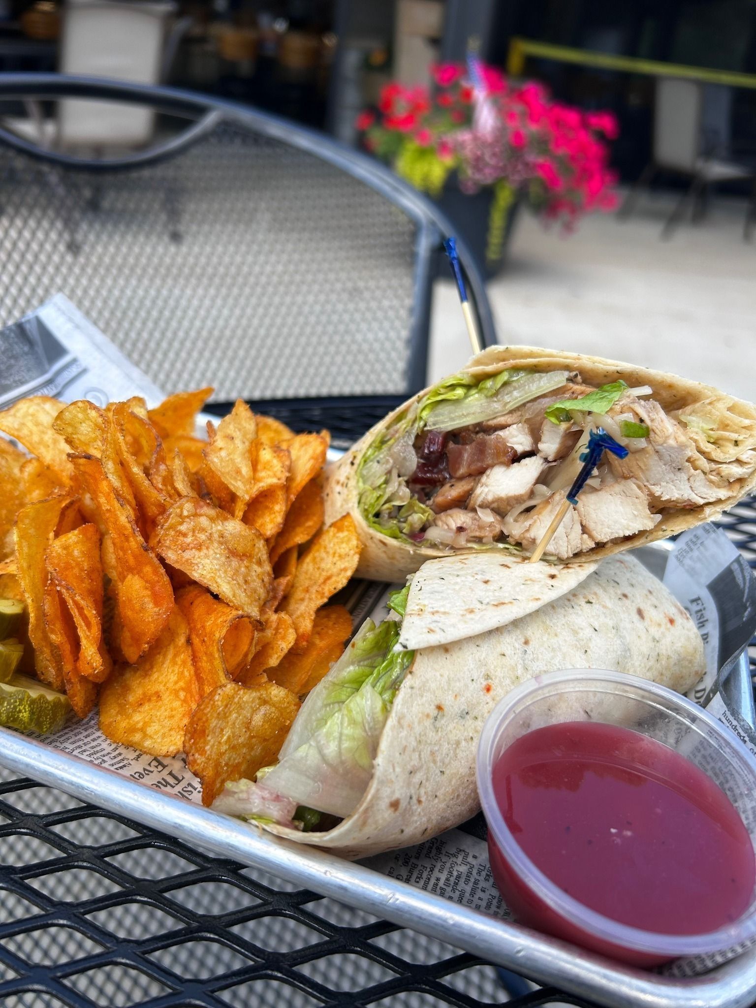 Gyro wrap with fries and red dipping sauce on a patio table