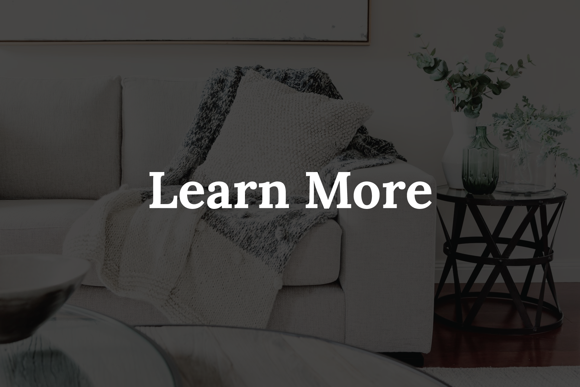 Cozy living room with cream sofa, throw blanket, side table, and the text 