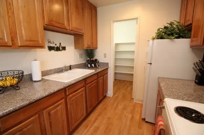 Kitchen with light-colored wooden cabinets and granite countertops; a pantry is visible in the background.
