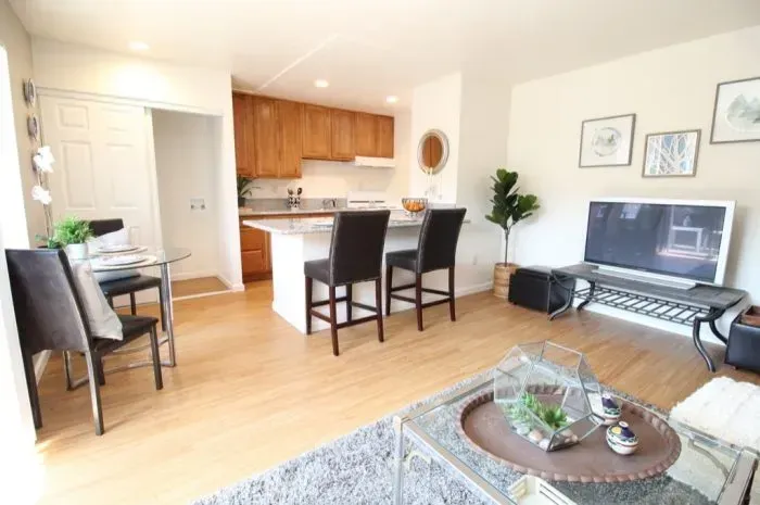 Open-concept living space with kitchen, dining area, and living room. Neutral colors and wood flooring.
