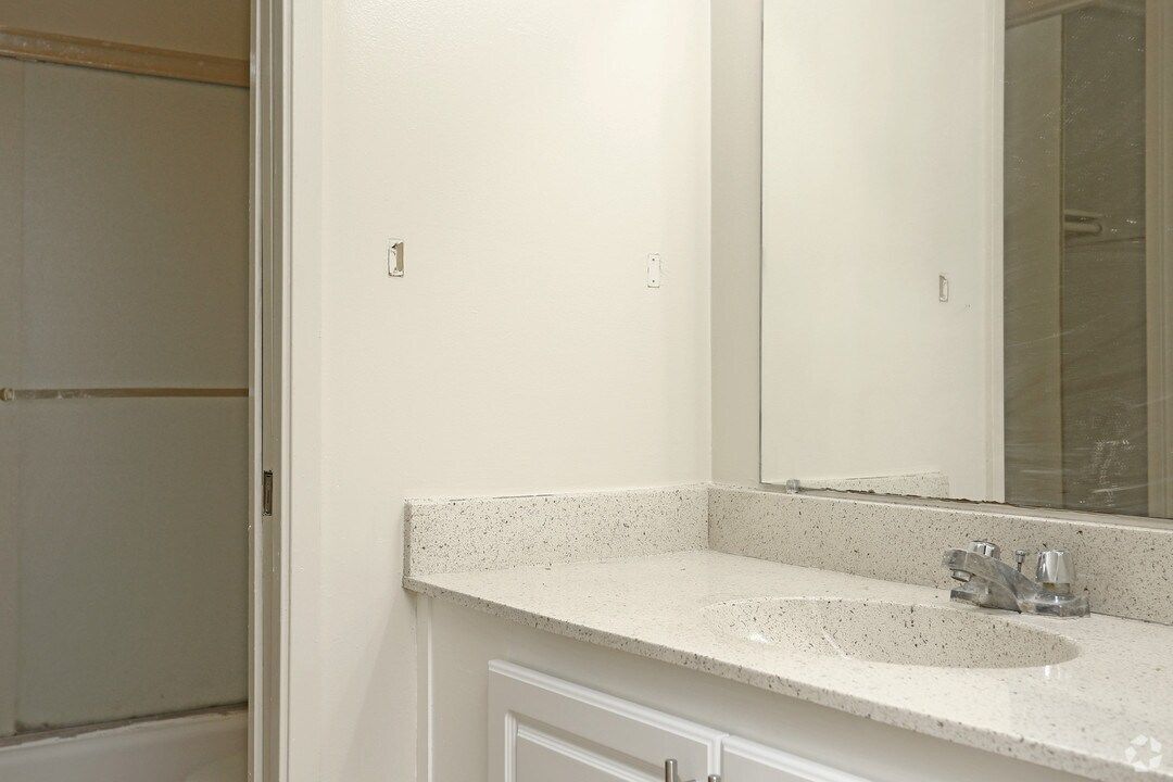 Bathroom with white countertop, sink, mirror, and shower.