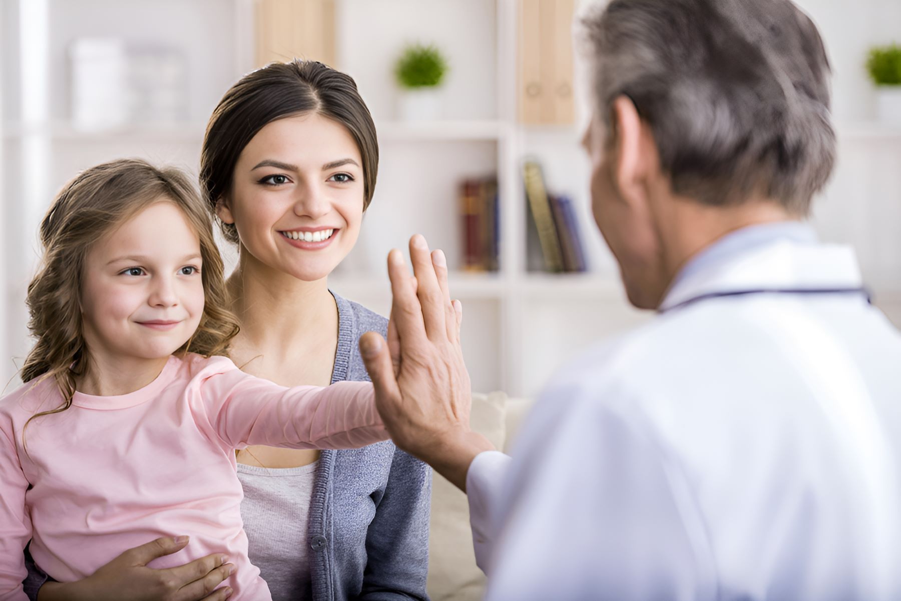 A Doctor is Giving a High Five to a Woman and a Little Girl — Newcastle Paediatric Occupational Therapy in Belmont, NSW