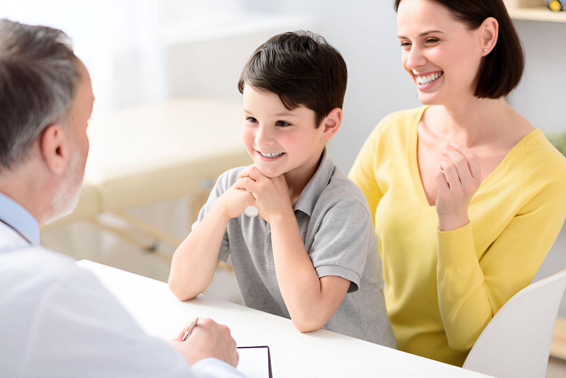 A Mother and Son Are Sitting at a Table Talking to a Doctor — Newcastle Paediatric Occupational Therapy in Mayfield, NSW