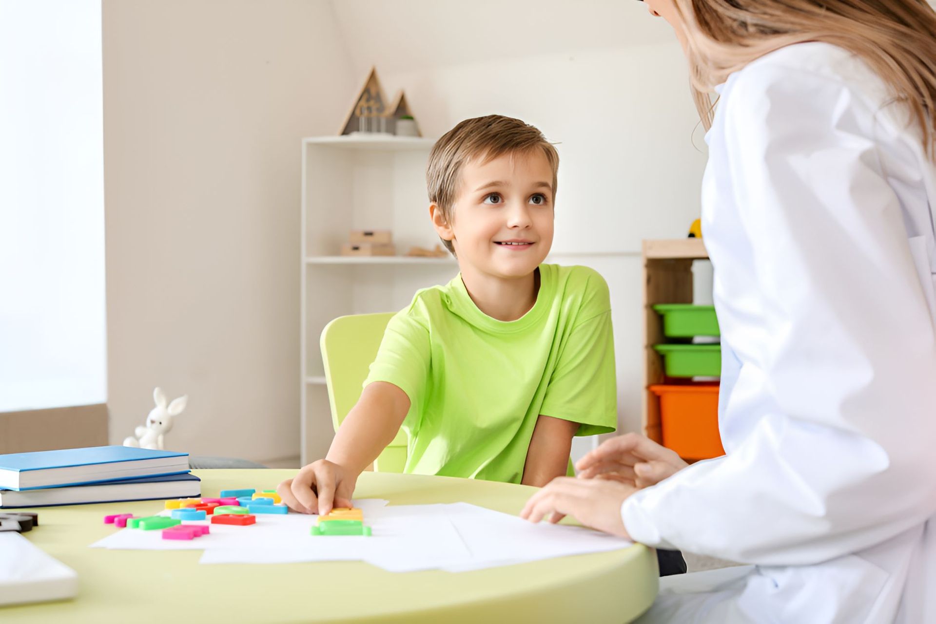 A Young Boy is Sitting at a Table Talking to a Female — Newcastle Paediatric Occupational Therapy in Swansea, NSW