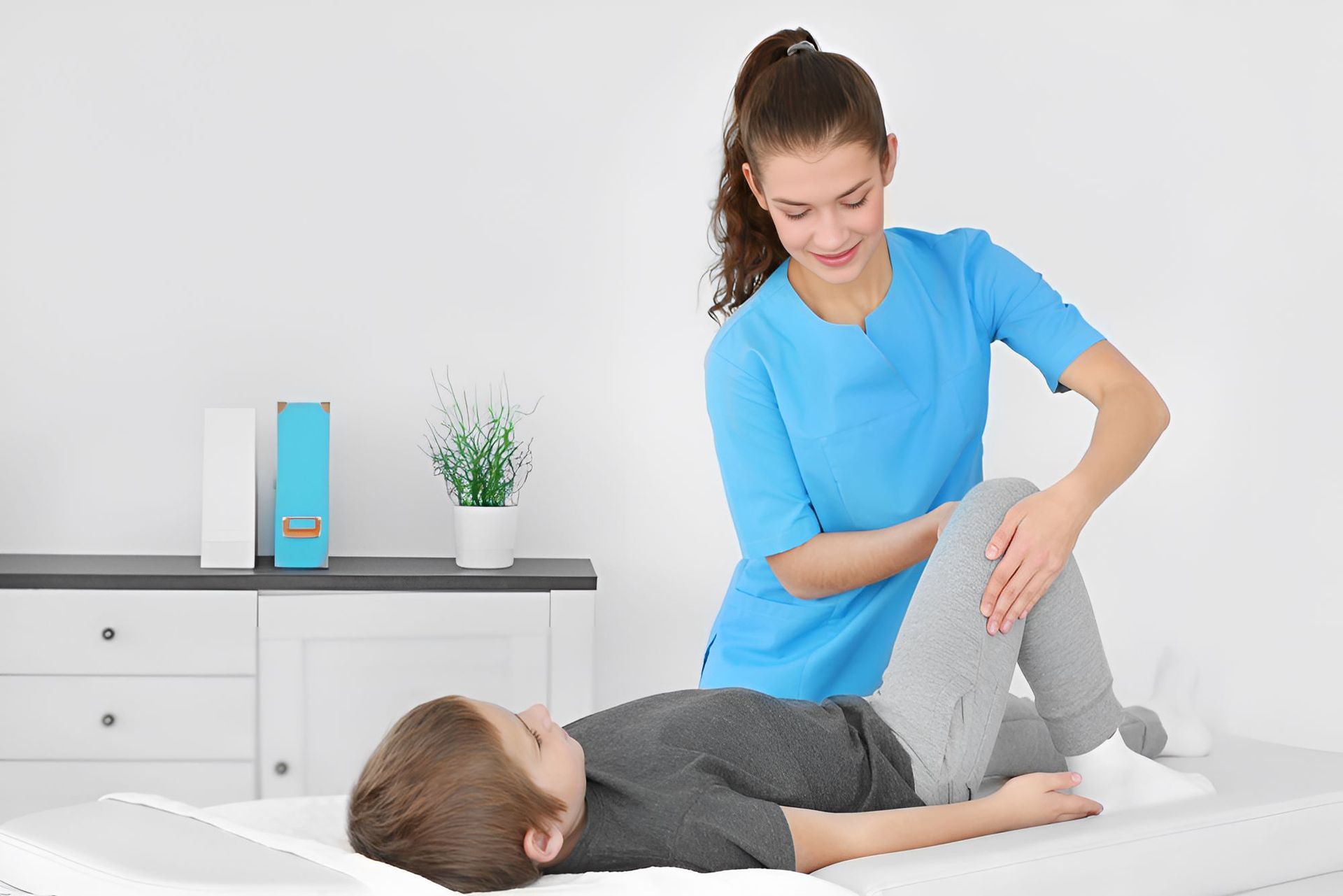 A Woman is Stretching a Child 's Leg on a Bed — Newcastle Paediatric Occupational Therapy in Floraville, NSW