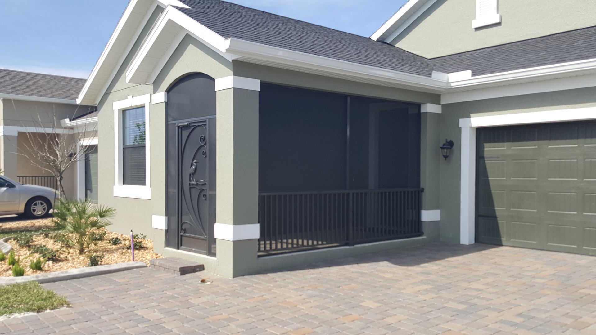 Modern suburban house exterior with gray siding, black porch railing, and a garage door