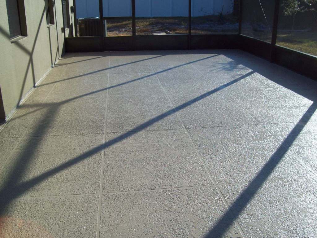 Sunlit outdoor patio with concrete floor, black railing, and long diagonal shadows