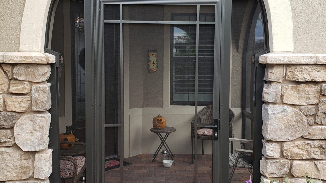 Screened front porch with a small decorative table and lamp between stone columns