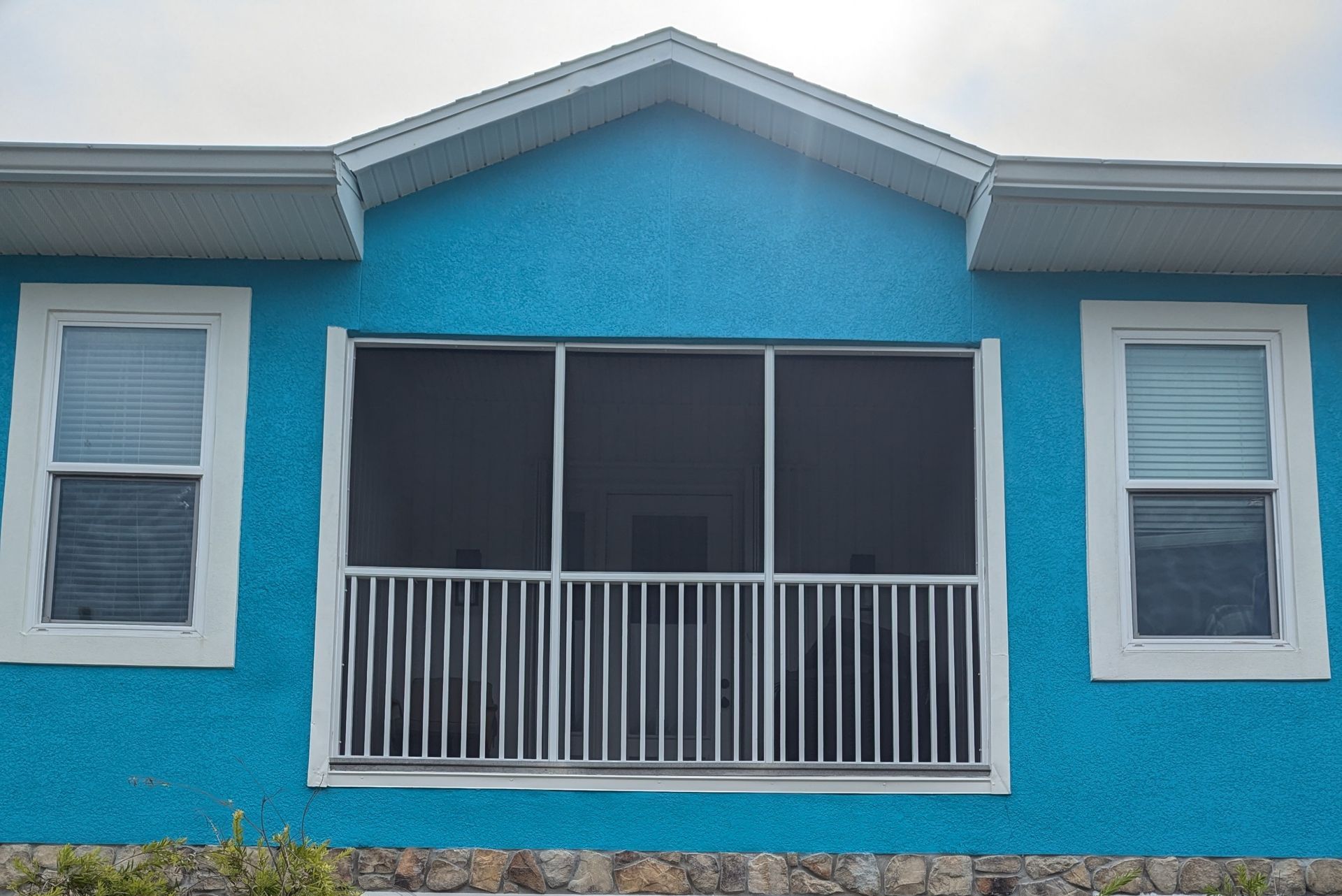 Blue house exterior with a screened front porch and white-trimmed windows