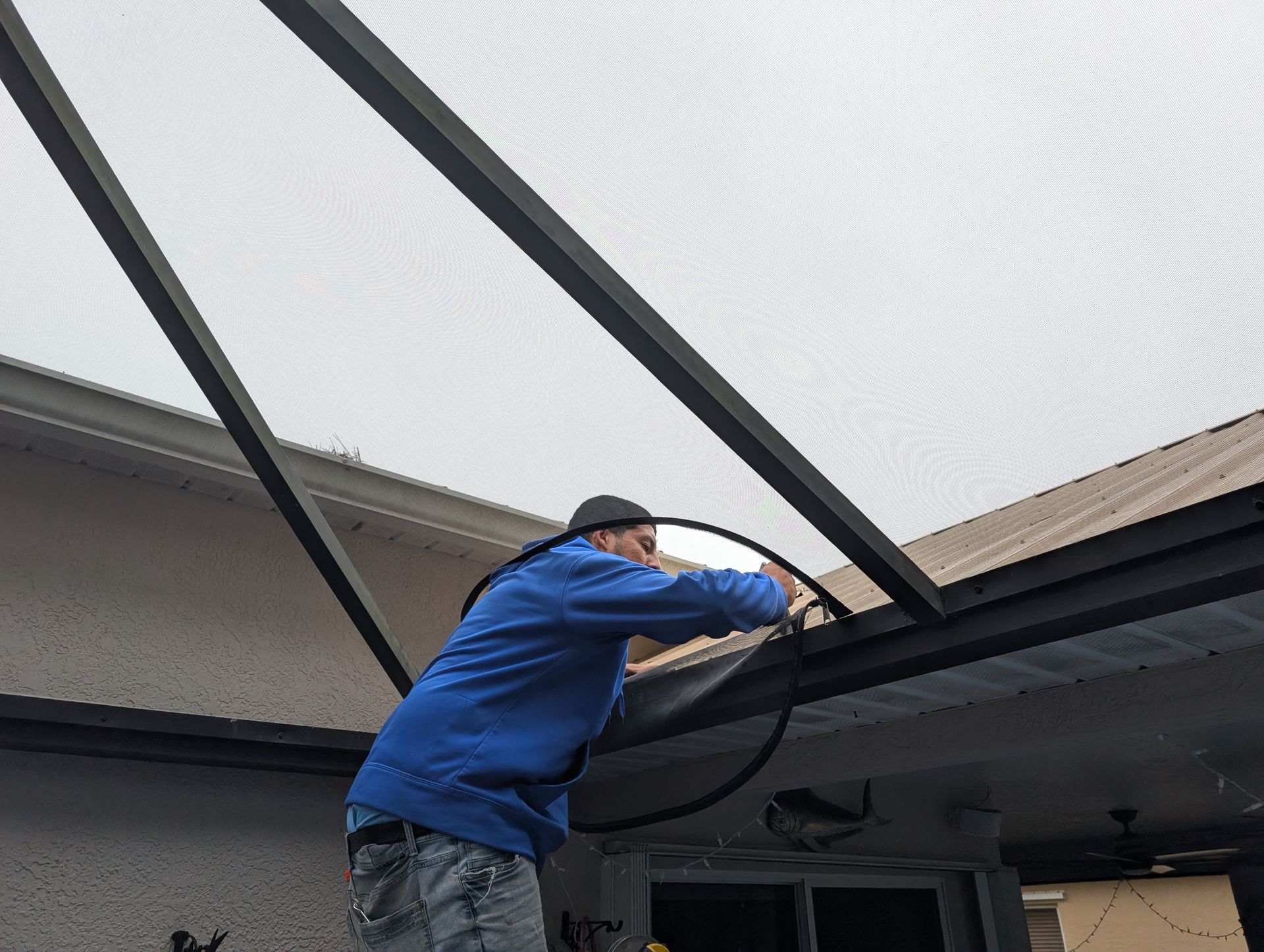 Person in a blue jacket working on a rooftop skylight frame.