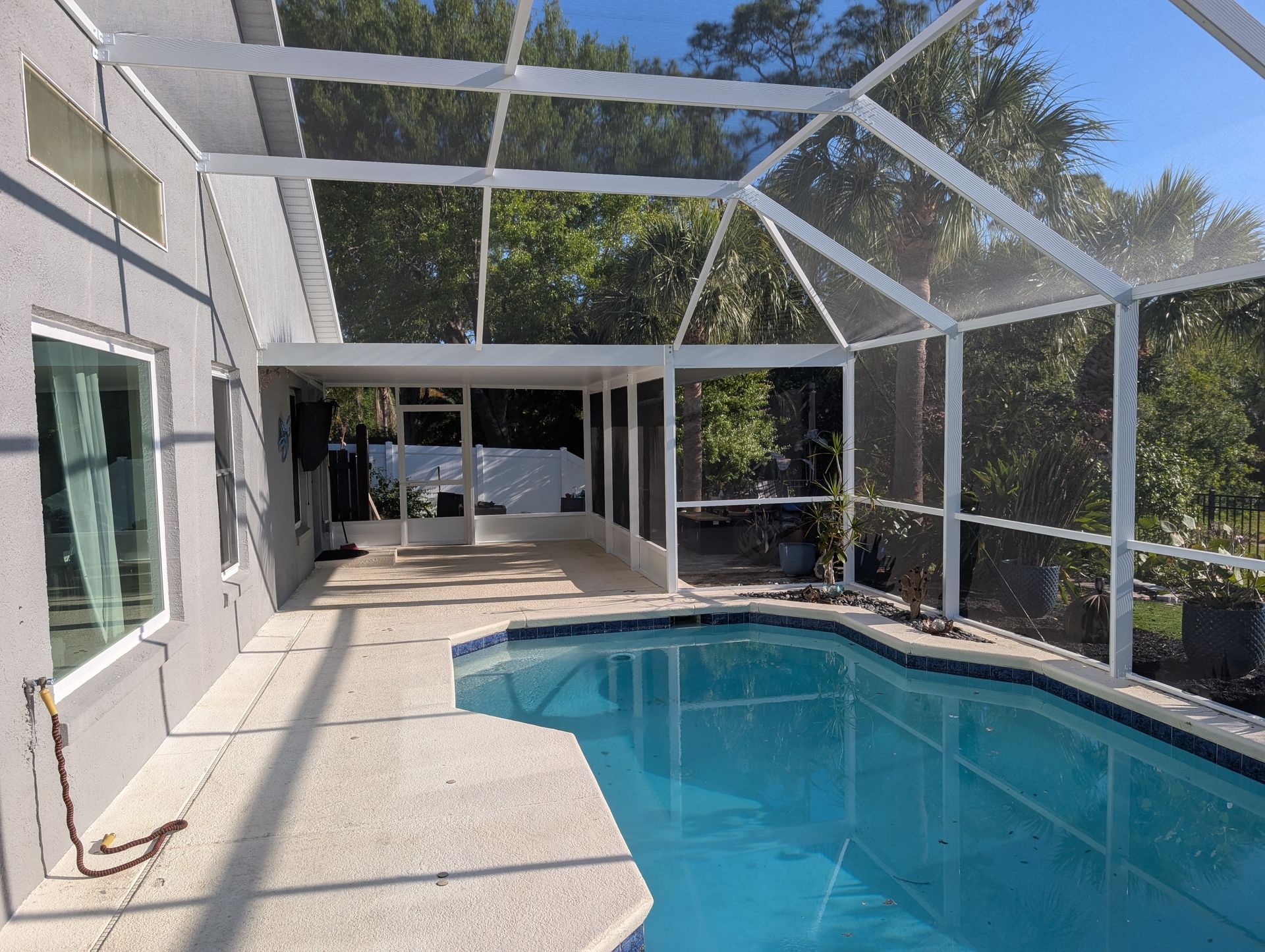 Screened backyard patio with a turquoise pool and modern covered seating area