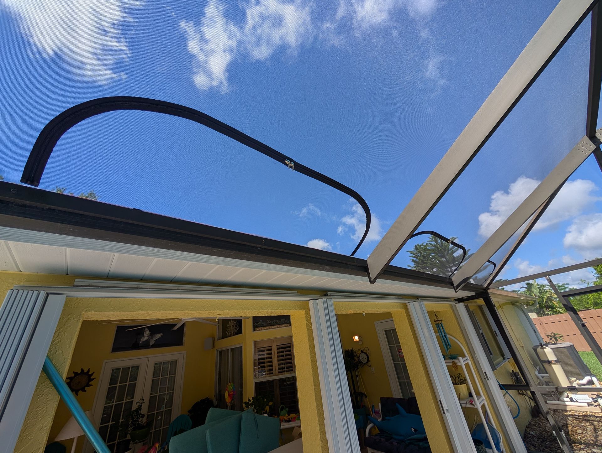 House patio with a partially installed black metal pergola frame against a blue sky