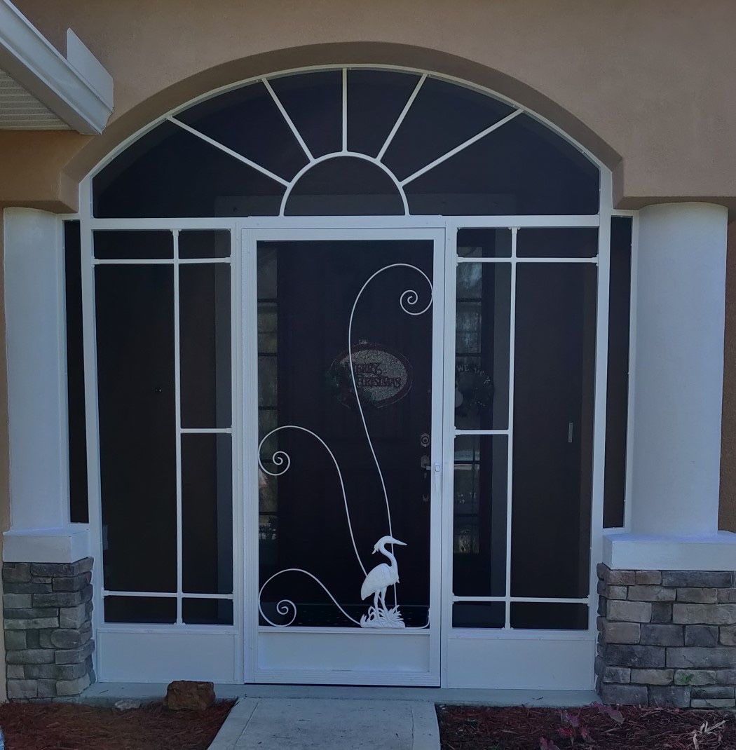 Front entrance with a white metal security door, arched window, and stone-trimmed stucco exterior.