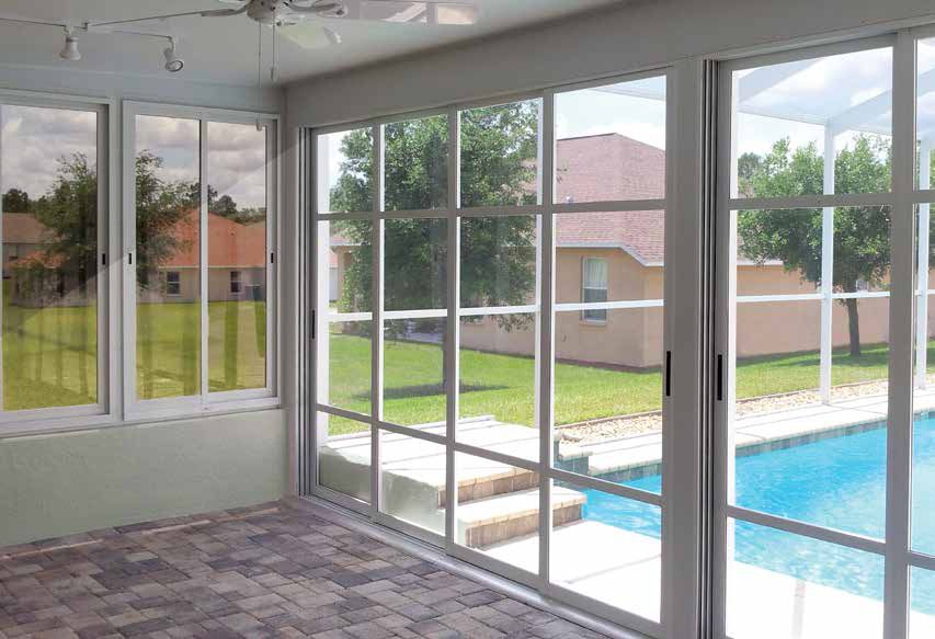 Sunroom with large windows overlooking a backyard pool and neighboring houses