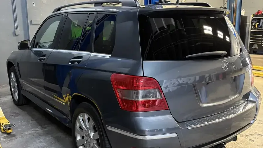Gray SUV parked indoors, rear three-quarter view, with tinted windows and roof rack.