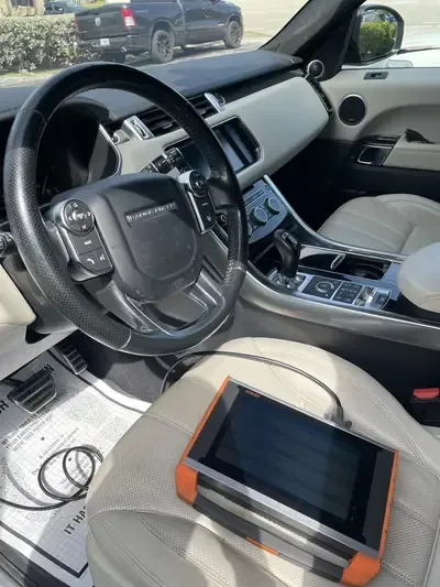 Car interior with black-and-white seats, steering wheel, center console, and a tablet on the passenger seat.