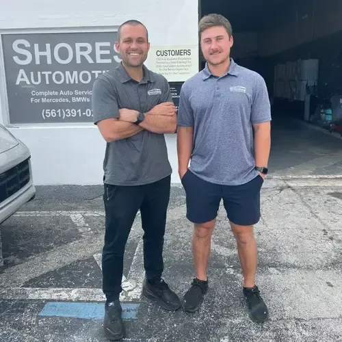 Two men standing outside Shore Automotive, smiling in front of the shop entrance