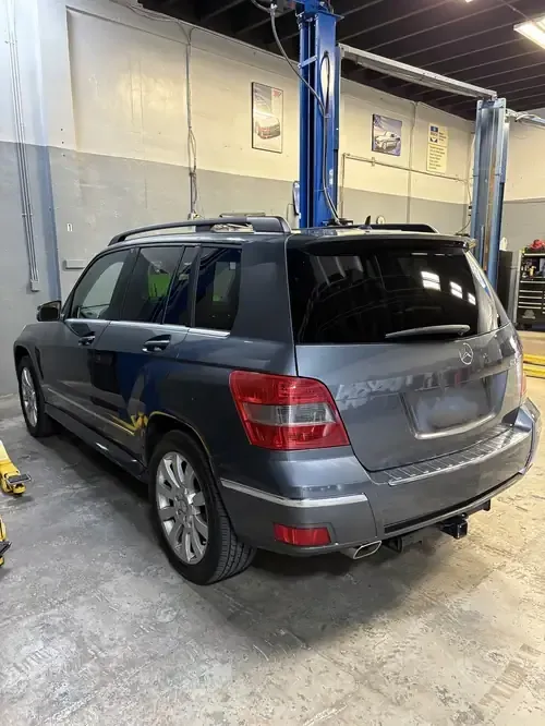 Gray SUV parked inside an auto repair shop, viewed from the rear-left side.