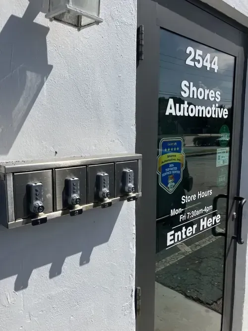 Building entrance for Shores Automotive with door signs and call box on gray wall