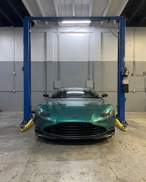 Green sports car centered in an auto shop lift bay
