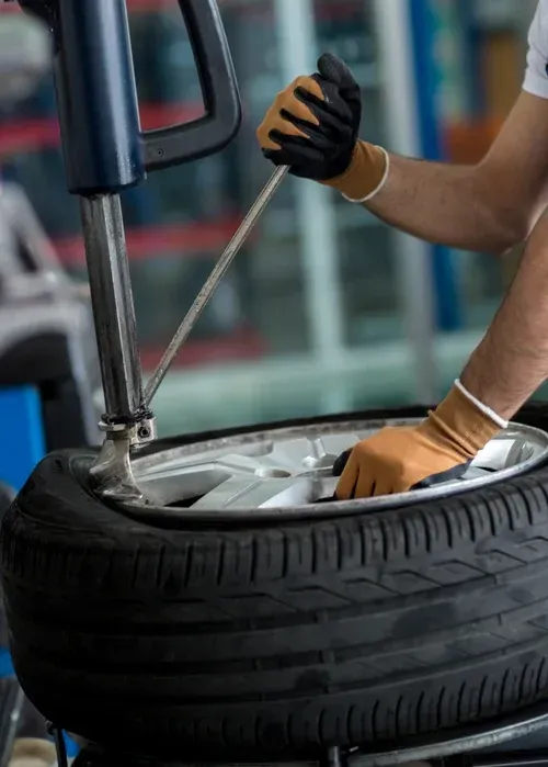 Mechanic changing a car tire with a wrench in a garage