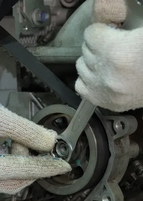 Gloved hands using a wrench to tighten a nut on a mechanical wheel assembly