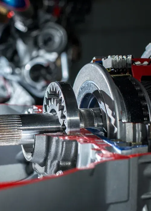 Close-up of metal gears and a shaft inside a mechanical device with red housing