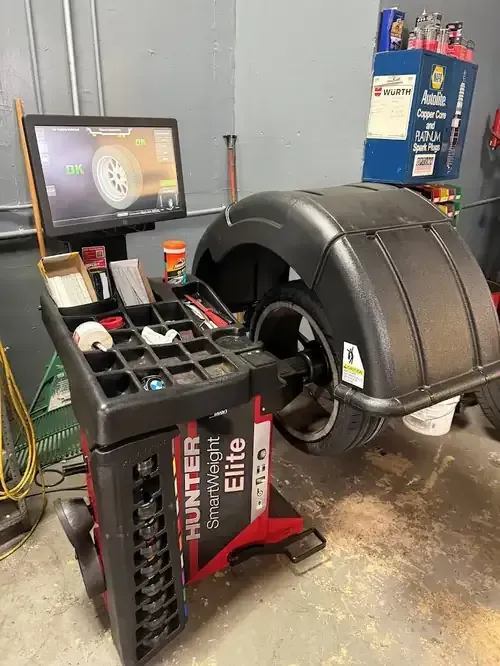 Hunter Elite tire balancing machine in a garage, with monitor and shop equipment nearby