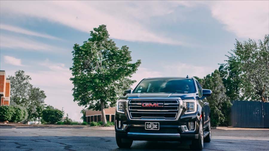 Black GMC pickup truck parked on a street with trees and a blue sky in the background