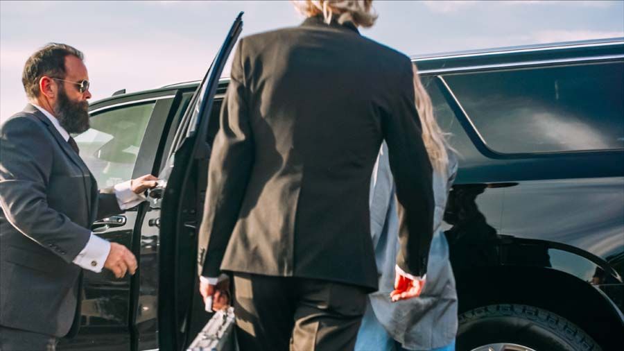 Men in suits opening a black SUV door, one holding a small child outside.