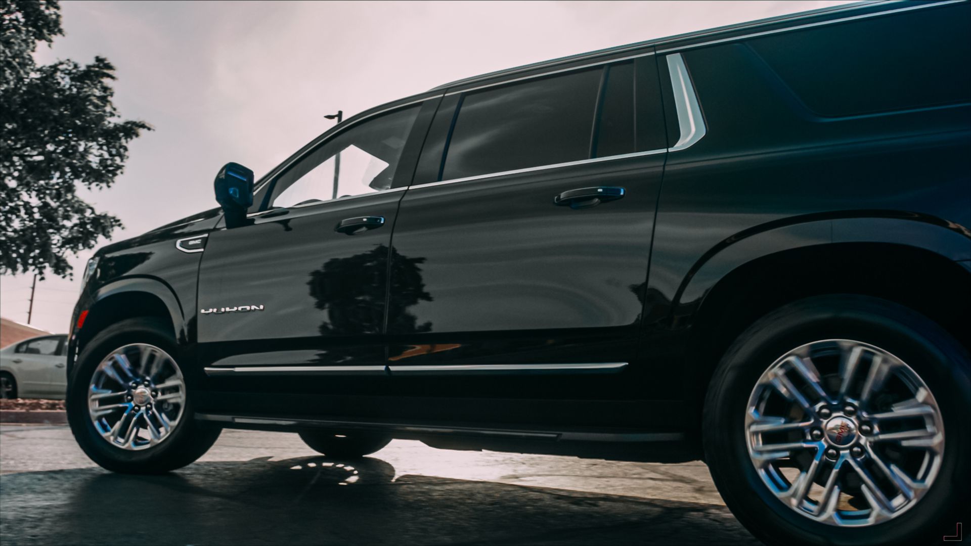 Black SUV parked on a wet street, side view, with chrome wheels and tinted windows.