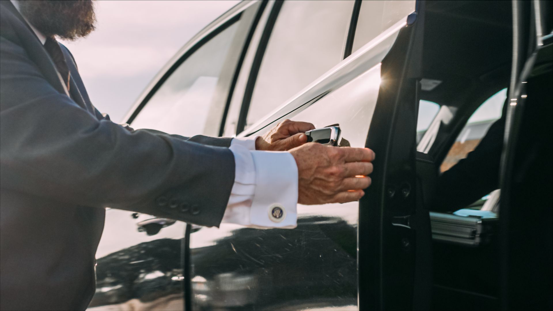 Person opening a black car door, holding a key fob near the handle.
