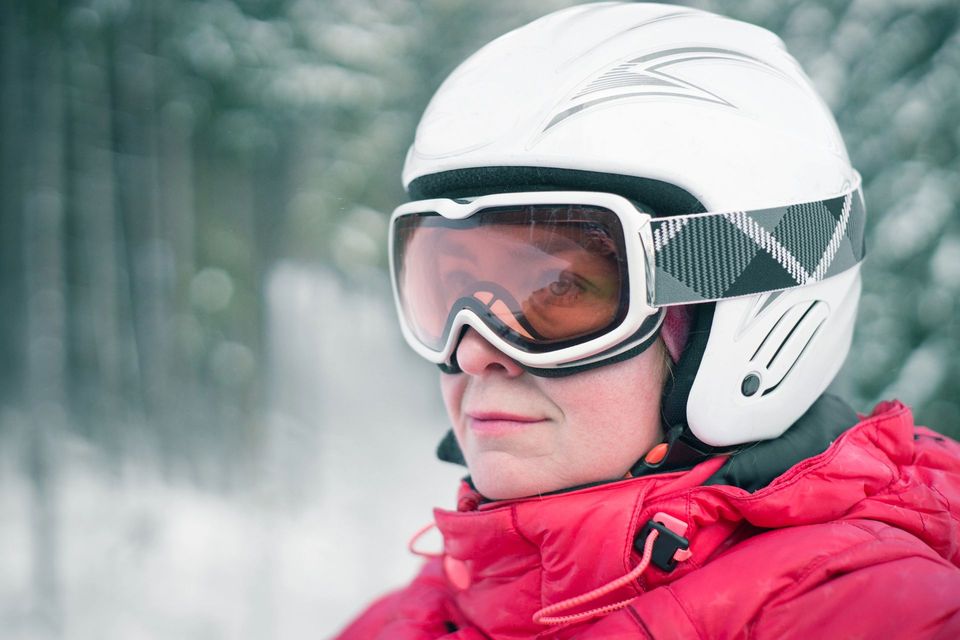 Persona con casco e occhiali da sci bianchi, che indossa una giacca rossa, in piedi sotto la neve.