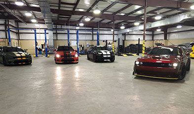 Cars with racing stripes inside a well-lit garage | Old School Automotive & Tire