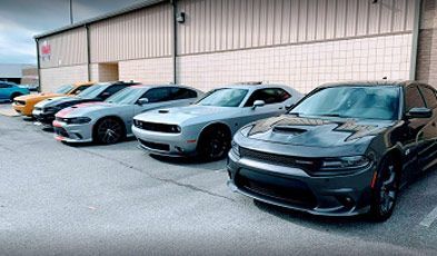Several Dodge muscle cars of various colors parked in a row | Old School Automotive & Tire
