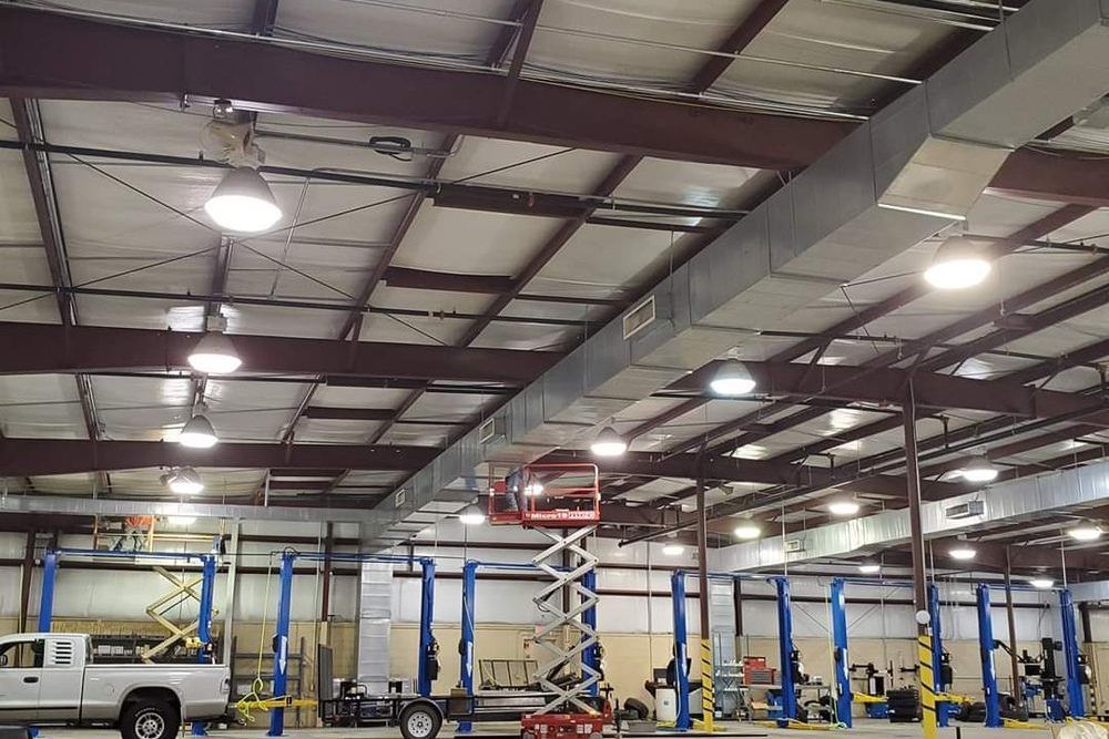 Interior of an auto shop with vehicles on lifts, a scissor lift, and overhead lighting | Old School Automotive & Tire