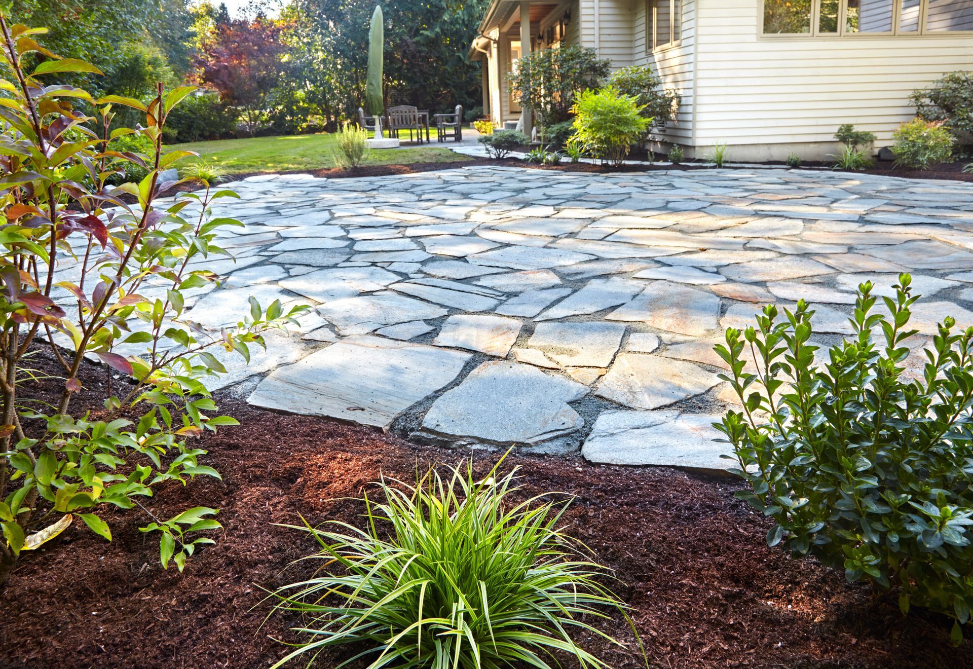 A stone patio with a house and plants | Louisville, KY | S & S Concrete Inc.