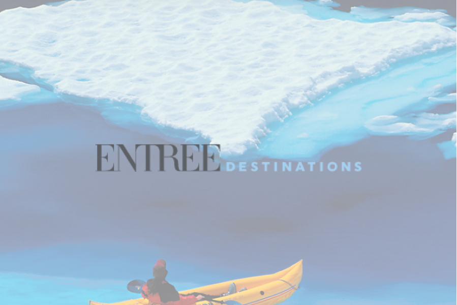 Kayaker in yellow boat under icebergs, 