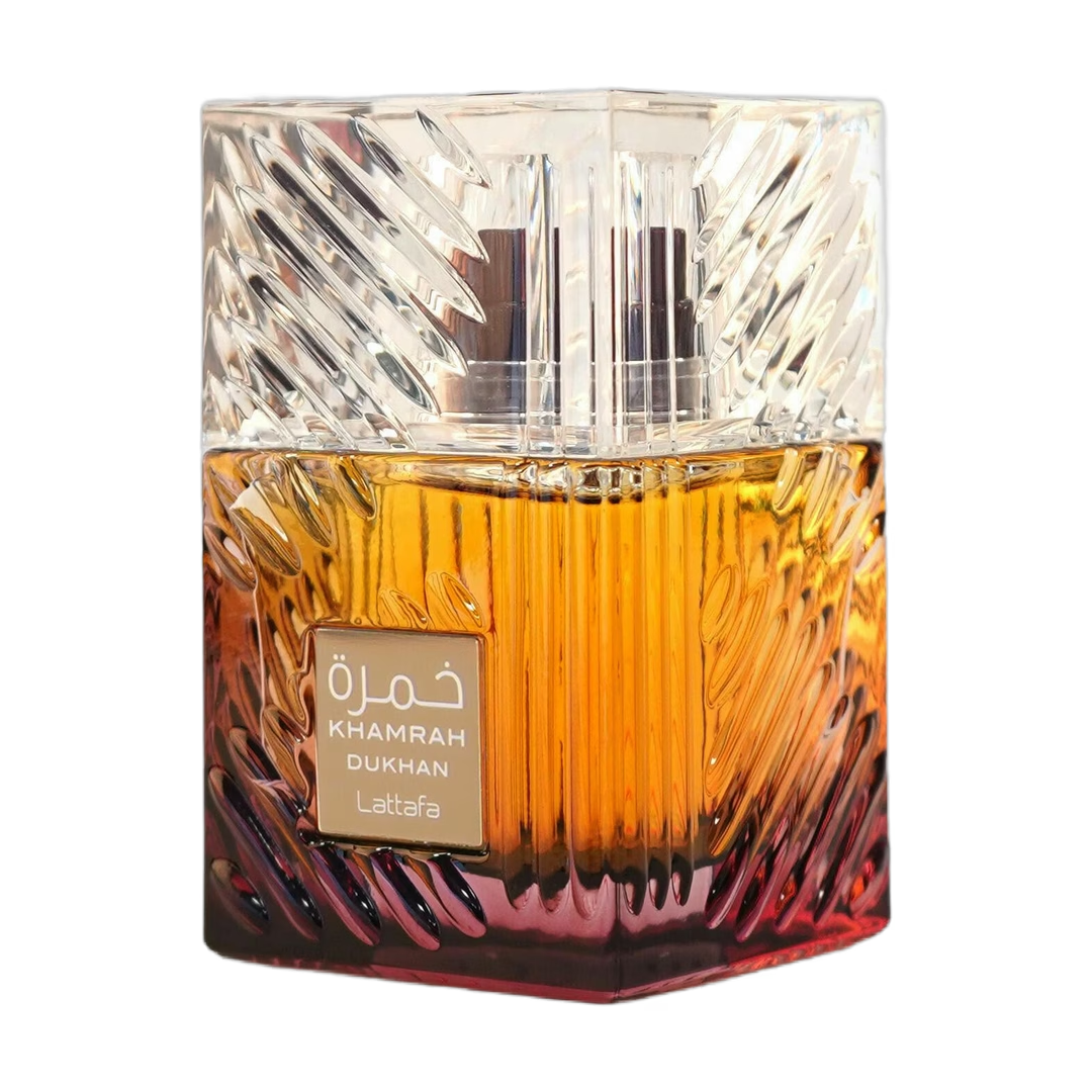 Frasco de perfume cuadrado de cristal con líquido color ámbar y un tapón transparente facetado, etiquetado en árabe.