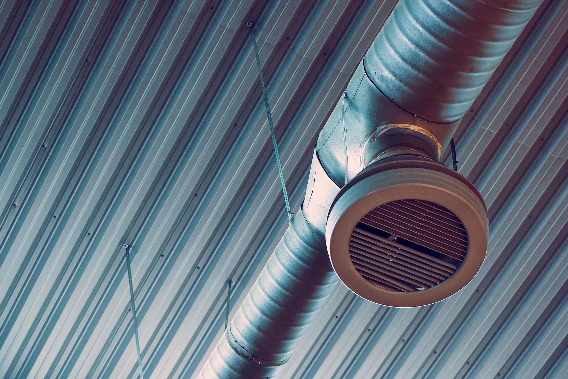 A metal pipe is hanging from the ceiling of a building.