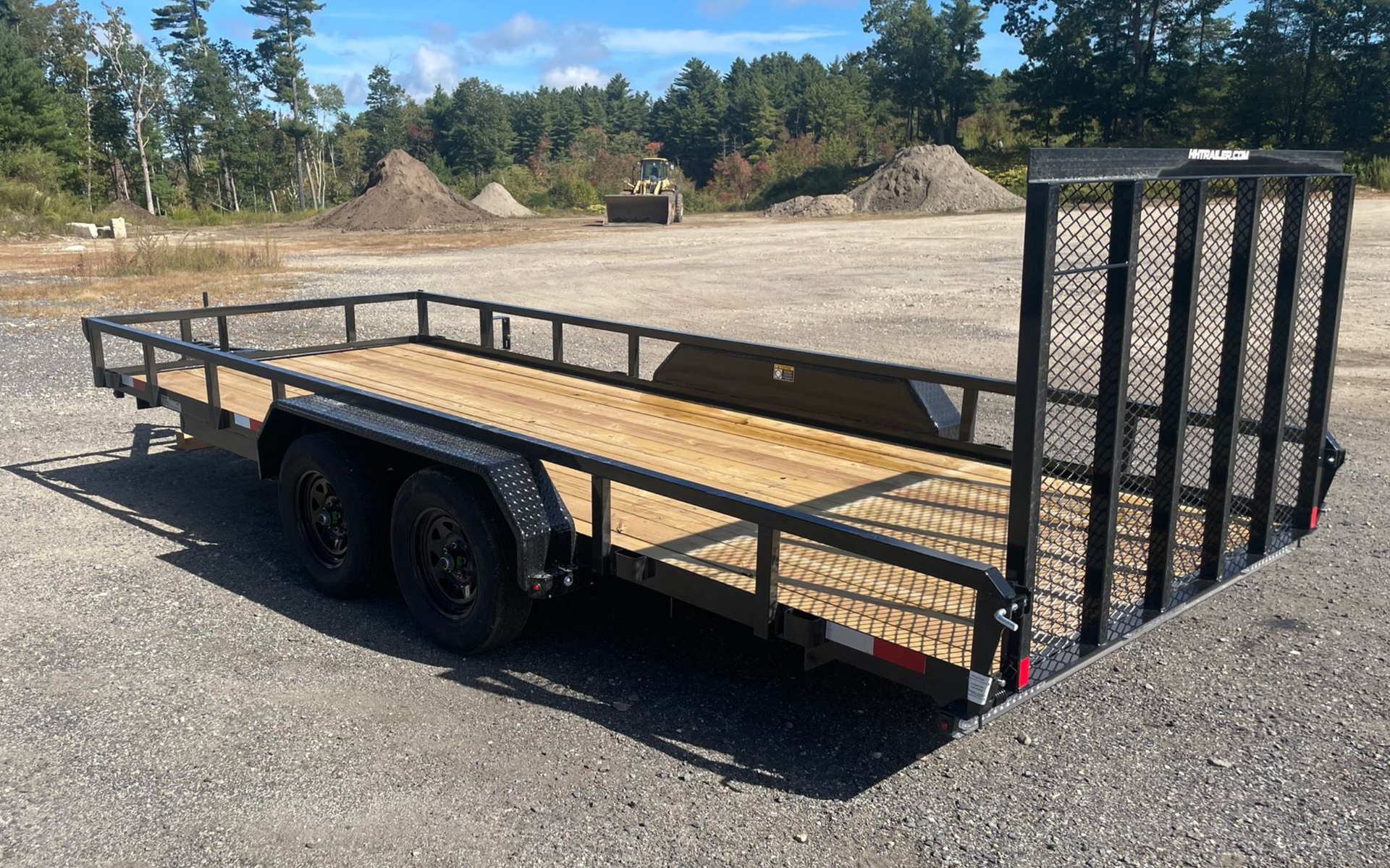 Flatbed trailer with black frame, wooden bed, and mesh side and front.