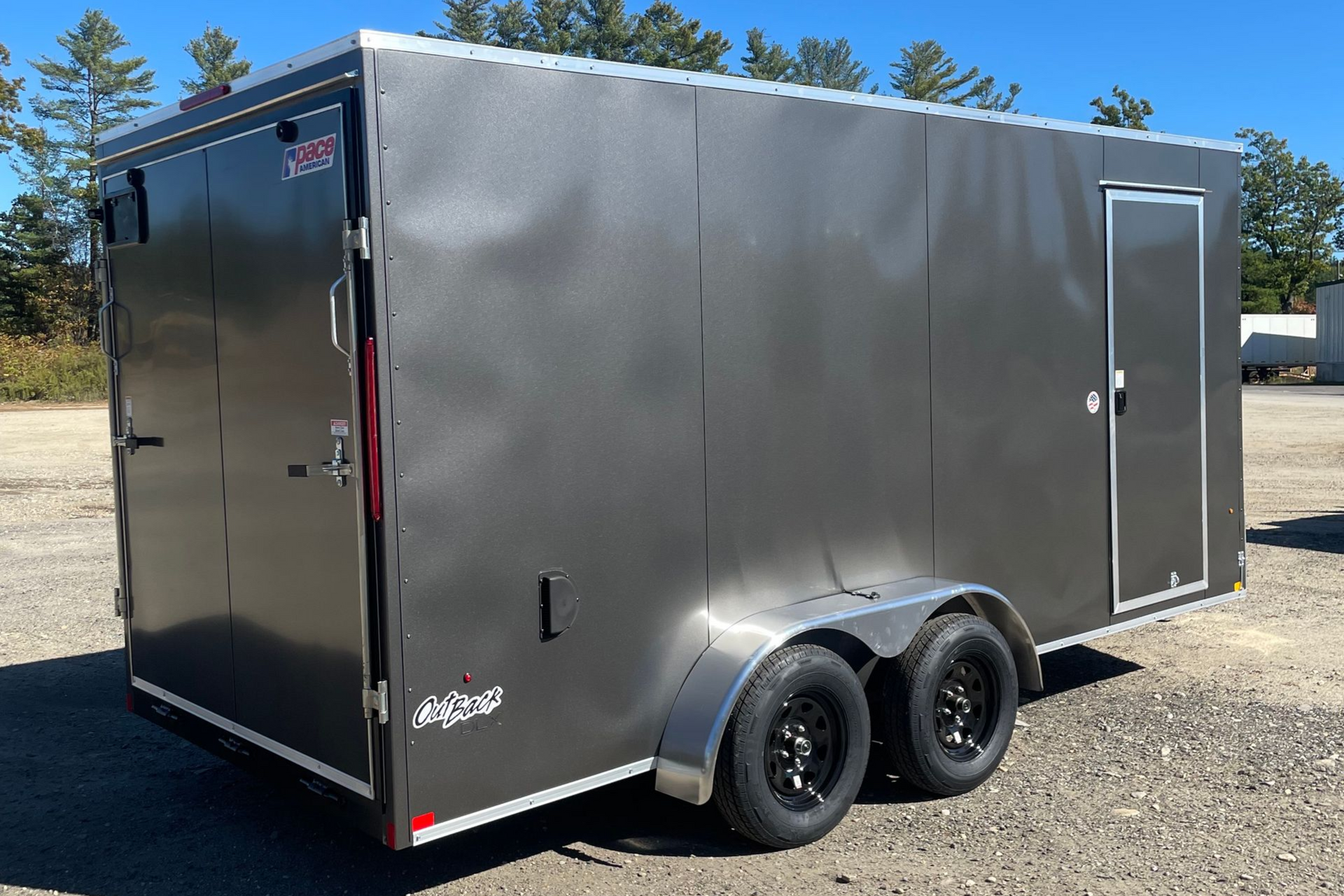 Dark gray enclosed cargo trailer with two wheels, standing outside.