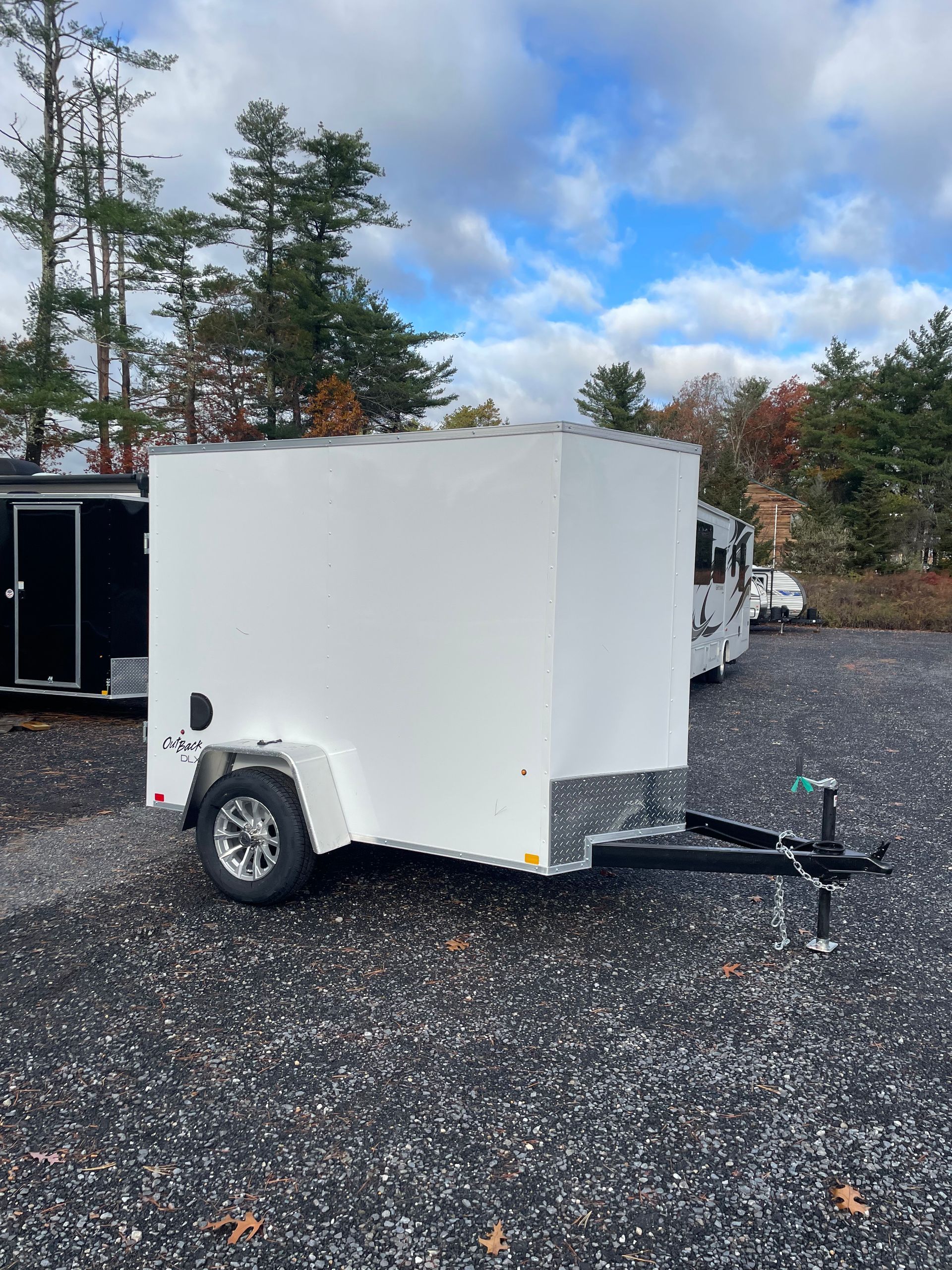 White enclosed cargo trailer parked on gravel.