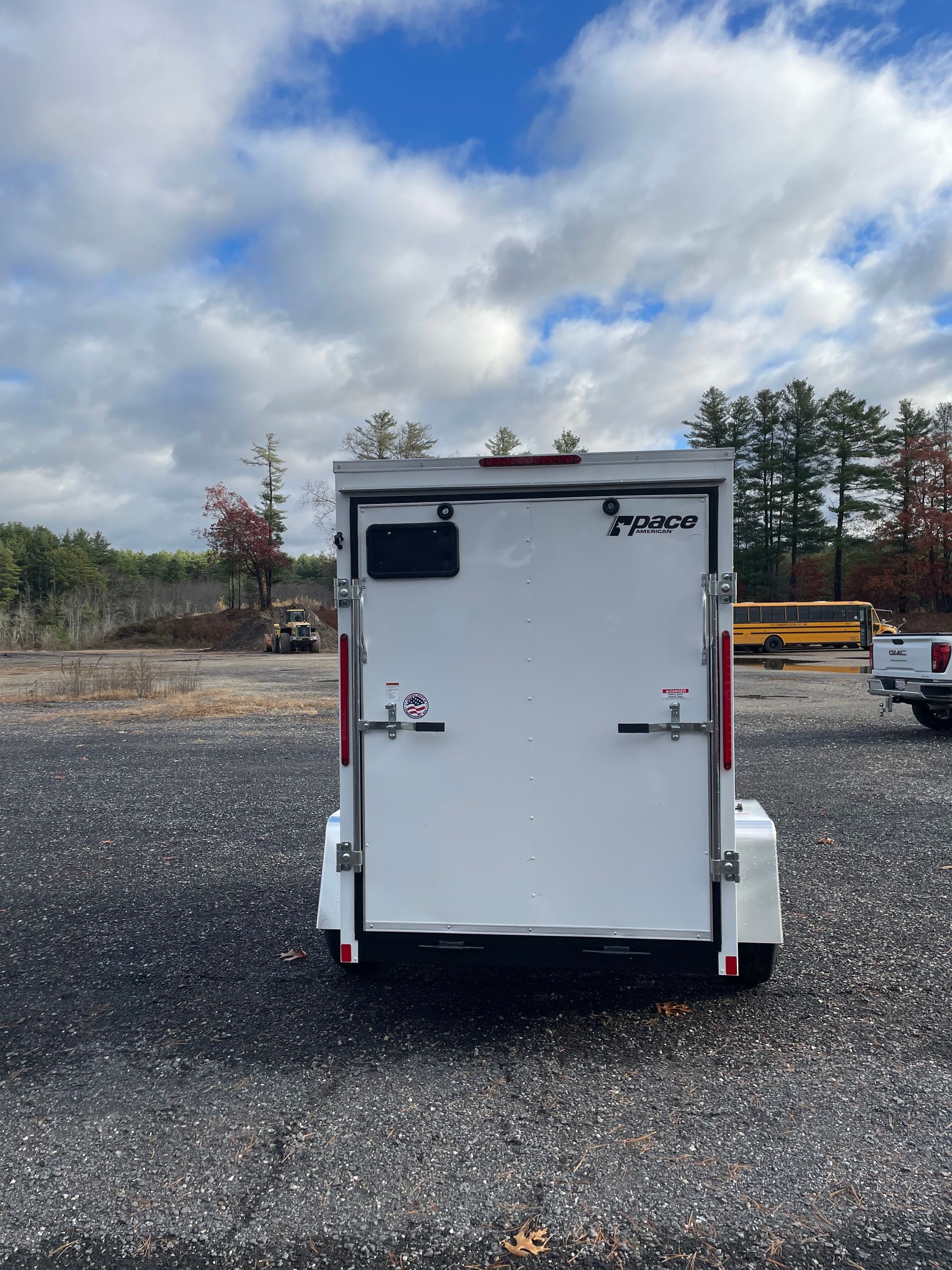 Rear view of a white cargo trailer against a cloudy sky.