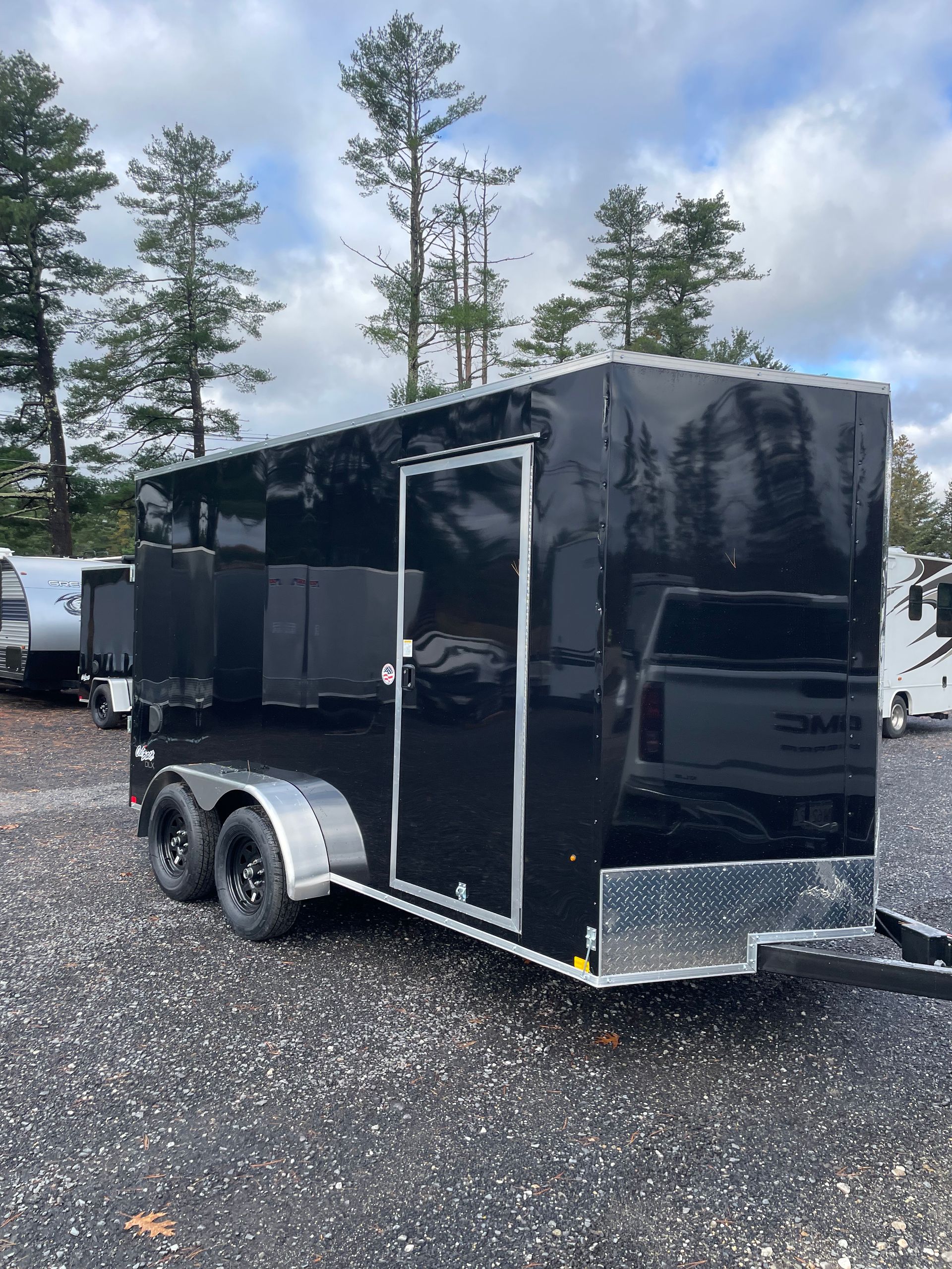 Black enclosed trailer parked on gravel.