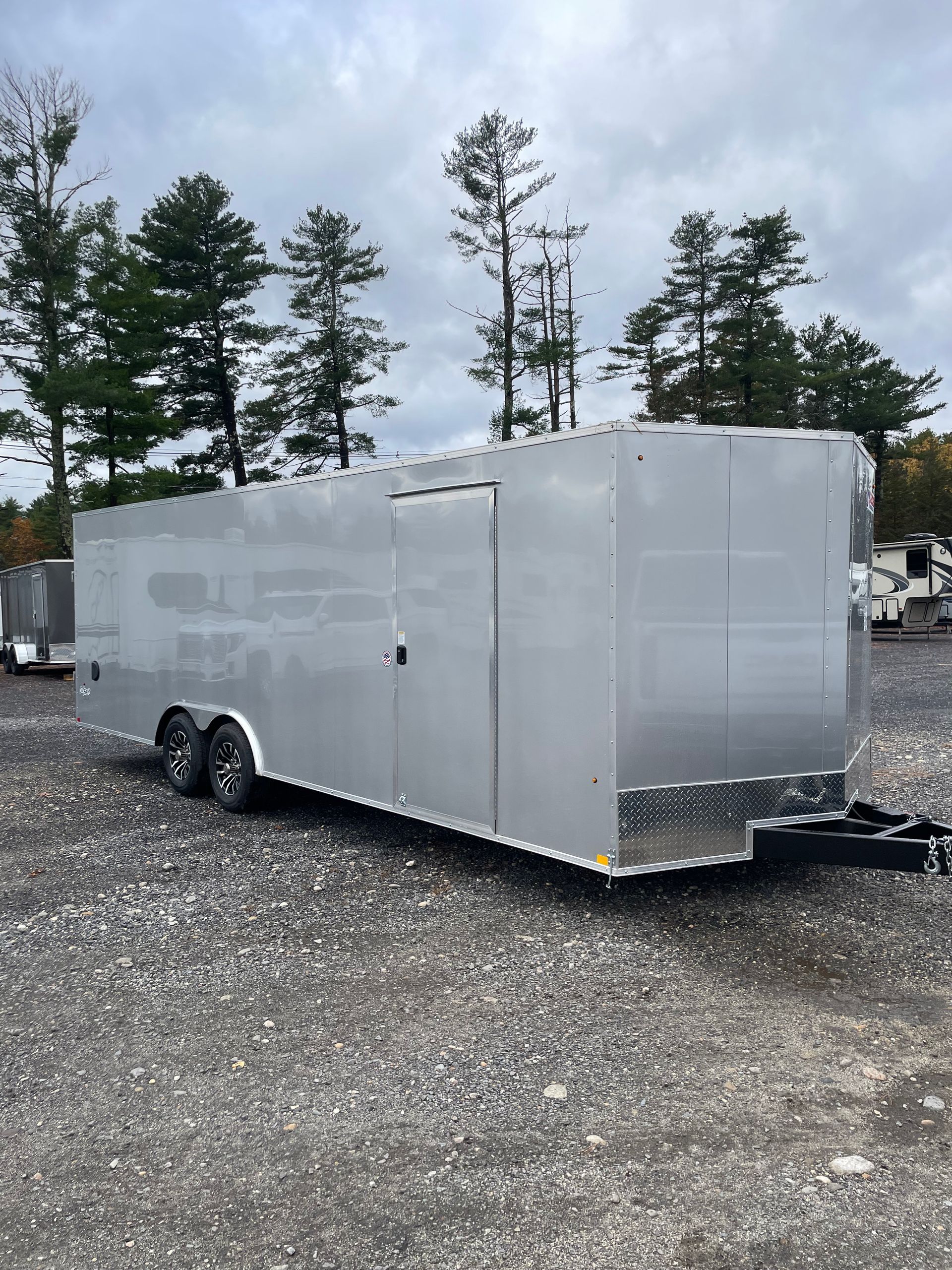 Silver enclosed cargo trailer parked on gravel.