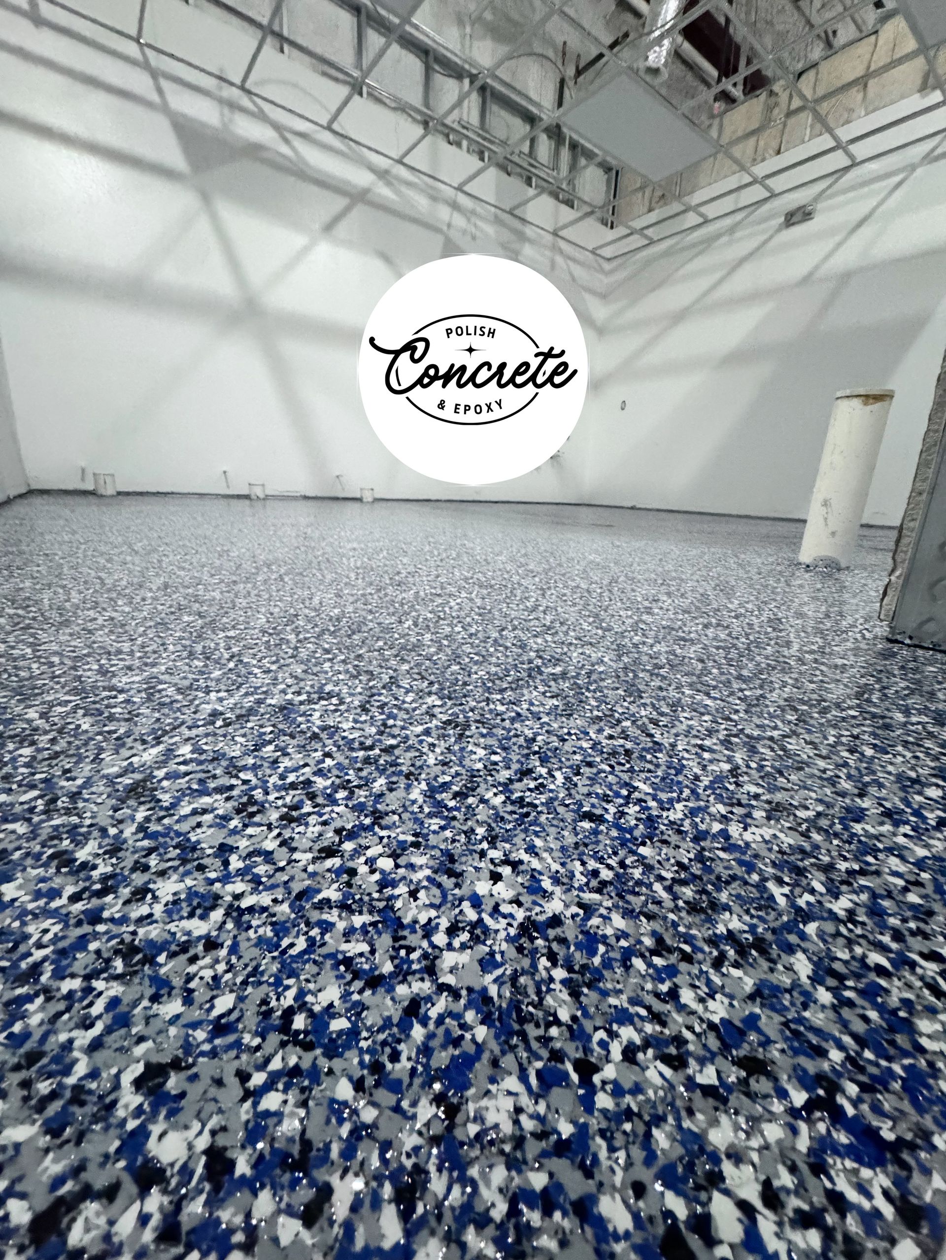 Empty industrial room with white walls and a blue-speckled epoxy floor