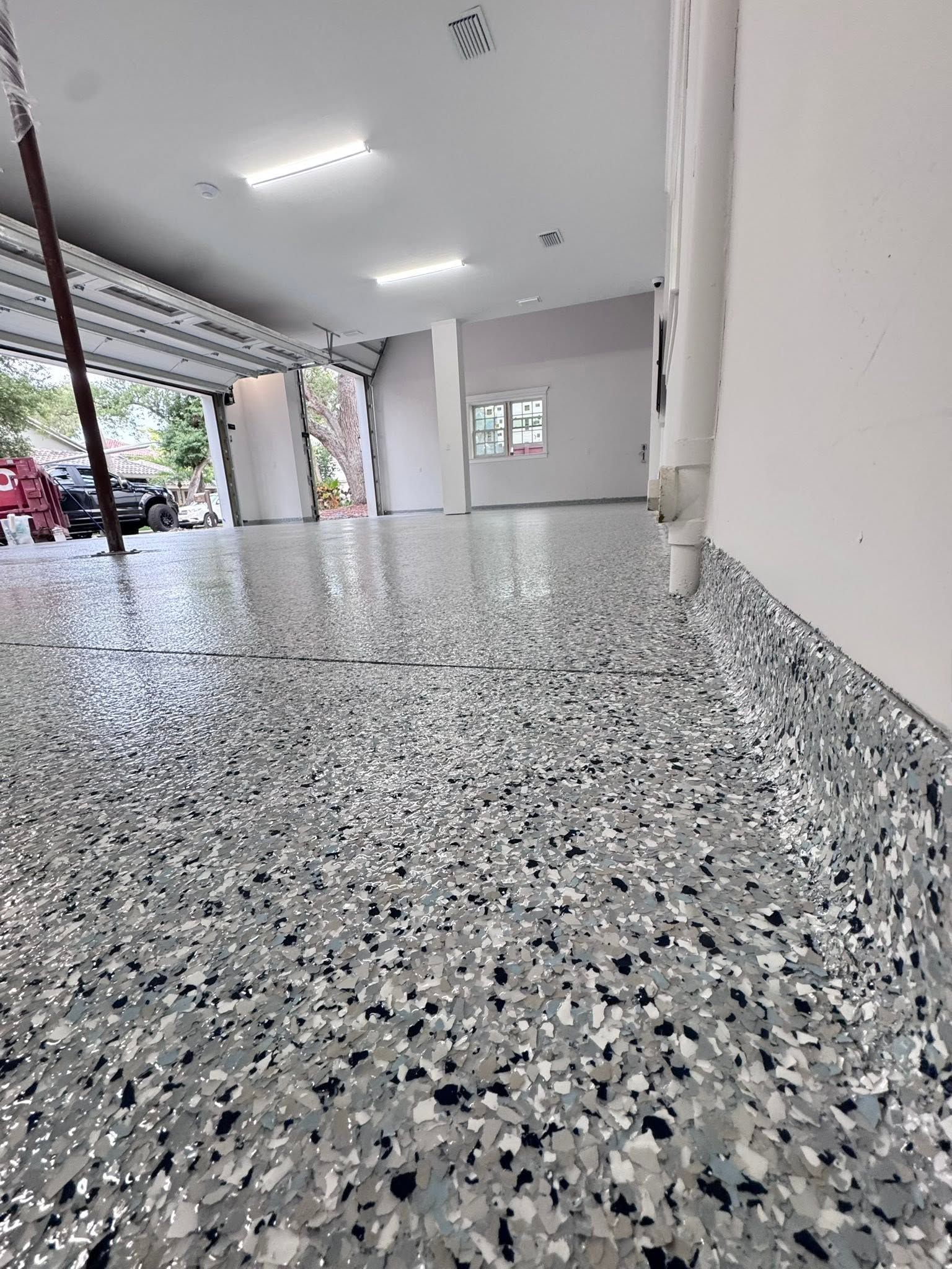 Empty covered walkway with speckled terrazzo floor, white walls, and an open view to the street.